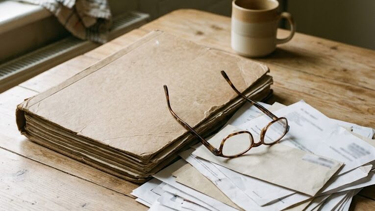 A worn folder of medical papers and reading glasses on a kitchen table